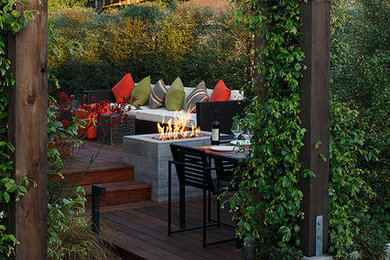 Example of a trendy backyard deck design in San Francisco with a fire pit and a pergola