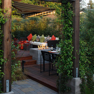 Ispirazione per una terrazza design dietro casa con un focolare e una pergola