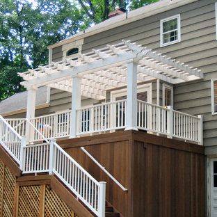 Idée de décoration pour une grande terrasse arrière tradition avec une pergola et jupe de finition.