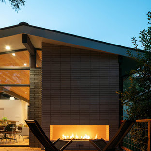 Example of a large mid-century modern backyard deck design in Dallas with a fireplace and no cover
