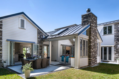 Cette image montre une grande terrasse arrière traditionnelle avec un foyer extérieur et une extension de toiture.