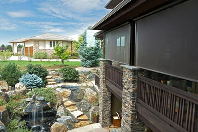 Imagen de terraza de estilo americano de tamaño medio en patio trasero y anexo de casas con fuente