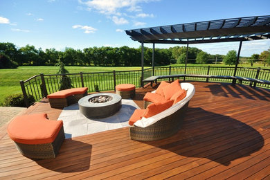 Example of a large transitional backyard deck design in New York with a fire pit and a pergola