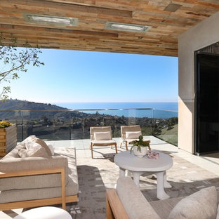 Inspiration for a large contemporary backyard deck remodel in Orange County with a fireplace and a roof extension