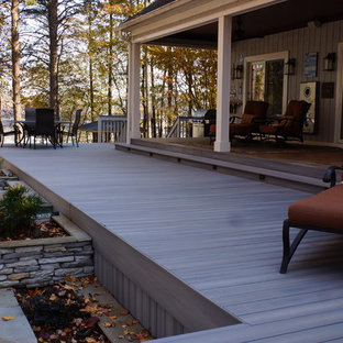Aménagement d'une très grande terrasse arrière classique avec une extension de toiture et jupe de finition.