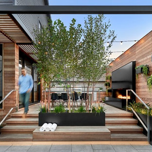 Esempio di una terrazza contemporanea nel cortile laterale con un caminetto e nessuna copertura