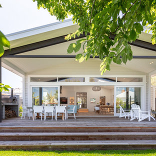 Deck - large transitional backyard deck idea in Auckland with a fireplace and a roof extension