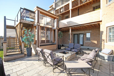 Deck - huge modern backyard deck idea in Toronto with a fire pit and a pergola