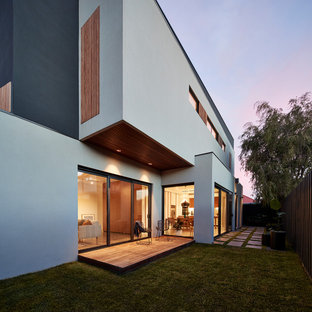 This is an example of a modern side yard deck in Melbourne with a roof extension.