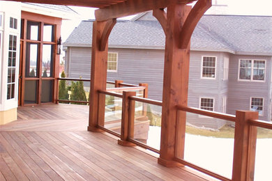 Example of a mid-sized backyard deck design in Other with a pergola