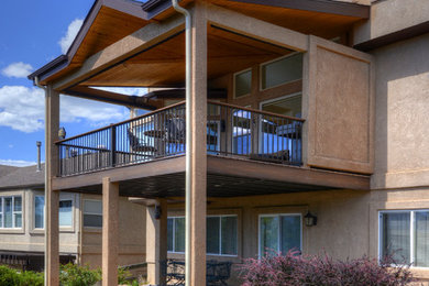 Example of a large classic backyard deck design in Denver with a roof extension