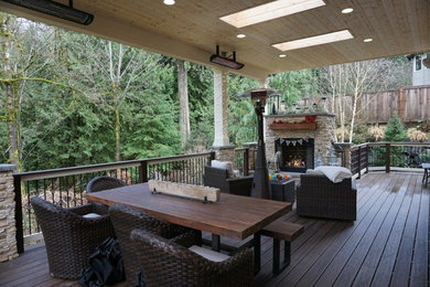 Example of a mid-sized trendy backyard deck design in Seattle with a fire pit and a roof extension