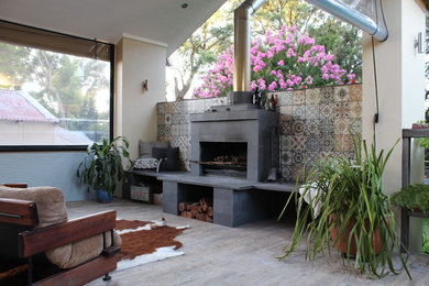 Example of a large mountain style backyard deck design in Sydney with a fire pit and a roof extension