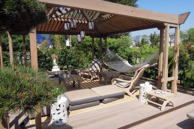 Modelo de terraza de estilo zen de tamaño medio en patio trasero con pérgola