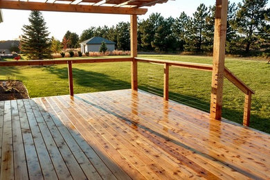 Deck - large rustic deck idea in Other with a pergola