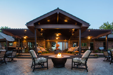Modelo de patio clásico grande en patio trasero con cocina exterior, suelo de hormigón estampado y pérgola