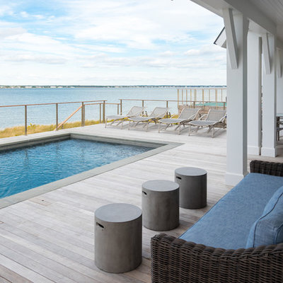 Example of a mid-sized beach style backyard deck design in New York with a roof extension