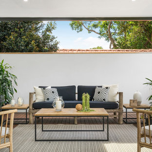 Beach style deck in Sydney with a roof extension.