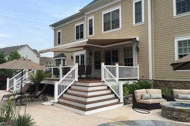 Example of a mid-sized backyard deck design in New York with an awning
