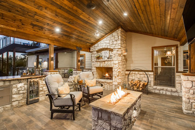 Example of a mountain style backyard deck design in Denver with a fire pit and a roof extension