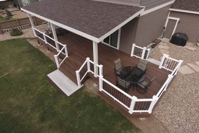 Example of a large classic side yard deck design in Denver with a roof extension