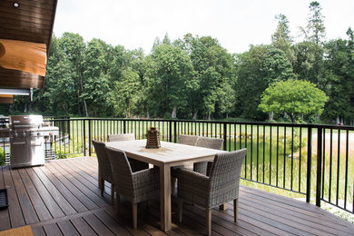 Example of a large mountain style backyard deck design in Vancouver with an awning