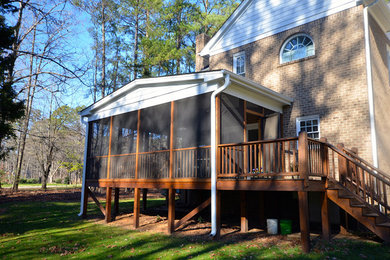 Example of a large backyard deck design in Raleigh with a roof extension