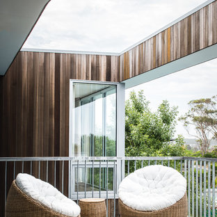 This is an example of a mid-sized beach style deck in Hobart with a roof extension.