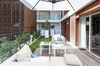 Immagine di una terrazza minimal dietro casa con un parasole