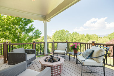 Example of a mid-sized trendy backyard deck design in Denver with a fire pit and a roof extension