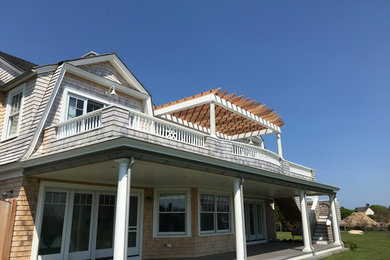 Inspiration for a large coastal backyard deck remodel in Providence with a pergola