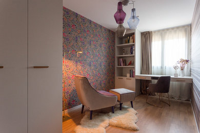 Modelo de despacho contemporáneo de tamaño medio con paredes multicolor, suelo de madera en tonos medios, escritorio empotrado y suelo marrón