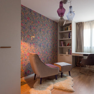 Modelo de despacho contemporáneo, de tamaño medio, con paredes multicolor, suelo de madera en tonos medios, escritorio empotrado y suelo marrón