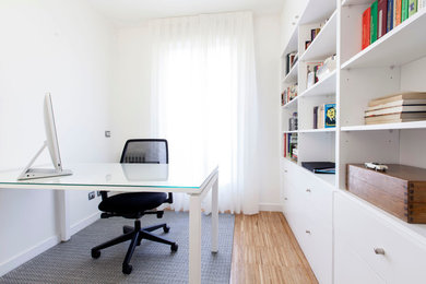 Modelo de despacho actual pequeño sin chimenea con paredes blancas, suelo de madera en tonos medios y escritorio empotrado