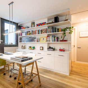 Diseño de despacho contemporáneo, de tamaño medio, con paredes beige, suelo laminado, suelo marrón y escritorio independiente