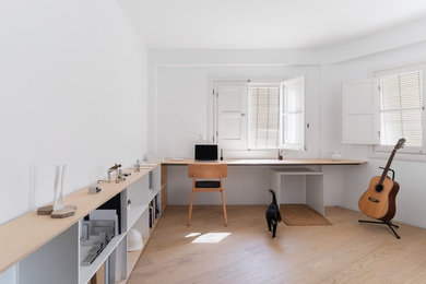 Foto de despacho nórdico grande con paredes blancas, suelo de madera en tonos medios, escritorio empotrado y suelo marrón