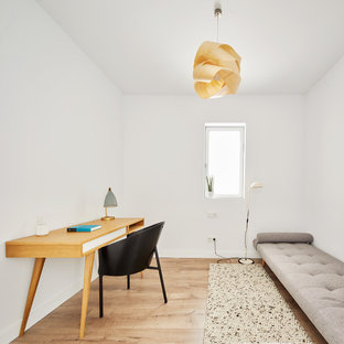 Imagen de estudio contemporáneo con paredes blancas, suelo de madera en tonos medios y escritorio independiente