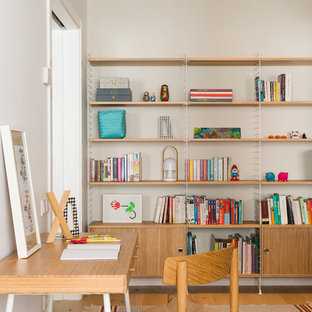 Diseño de estudio contemporáneo, grande, sin chimenea, con suelo de madera en tonos medios, suelo marrón, paredes blancas y escritorio independiente