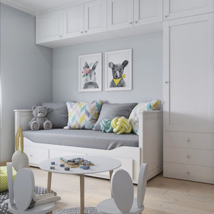 Immagine di una piccola cameretta per bambini da 1 a 3 anni scandinava con pavimento in laminato, pavimento beige e pareti bianche