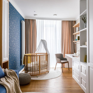 Immagine di una cameretta per bambini da 1 a 3 anni contemporanea di medie dimensioni con pareti blu, pavimento in laminato e pavimento marrone