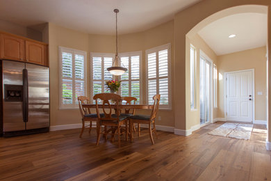 Cette image montre une grande salle à manger traditionnelle avec un sol en bois brun et une cheminée standard.
