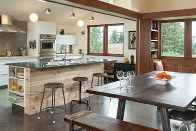 Photo of a medium sized contemporary kitchen/dining room in Seattle with white walls, plywood flooring, no fireplace and brown floors.