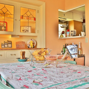 Immagine di una sala da pranzo boho chic chiusa con pareti arancioni