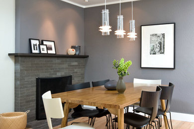 Contemporary dining room in San Francisco with grey walls, light hardwood flooring and a tiled fireplace surround.