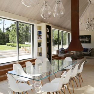 Design ideas for a medium sized contemporary open plan dining room in Gloucestershire with a stone fireplace surround, beige floors, beige walls and a two-sided fireplace.