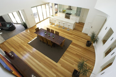 Offenes, Großes Modernes Esszimmer ohne Kamin mit weißer Wandfarbe und braunem Holzboden in Melbourne