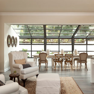 Foto di una grande sala da pranzo aperta verso la cucina mediterranea con pareti beige, pavimento in legno massello medio e cornice del camino in pietra