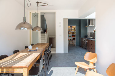 Contemporary kitchen/dining room in London with white walls, ceramic flooring and grey floors.