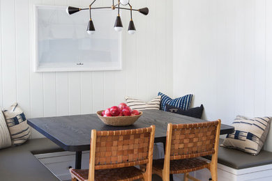 Diseño de comedor costero sin chimenea con paredes blancas, suelo de madera clara y suelo marrón