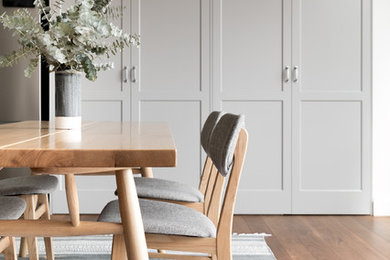 Inspiration pour une salle à manger ouverte sur le salon traditionnelle de taille moyenne avec un mur blanc, un sol en bois brun, un sol marron et un manteau de cheminée en bois.